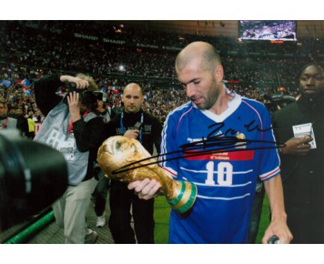 Football Zinedine Zidane signed 12x8 colour photo pictured holding the World Cup trophy while playing for France. Good condit