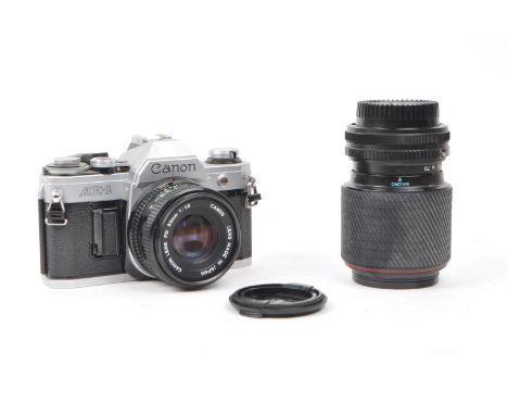 Canon - A vintage 20th century circa 1980s Canon AE-1 35mm SLR camera. The camera in silver colourway. Alongside a Canon FD 5