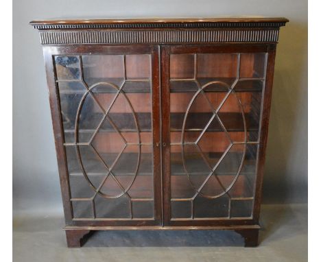 An Early 20th Century Mahogany Dwarf Bookcase, the moulded top above two astragal glazed doors enclosing shelves, raised upon