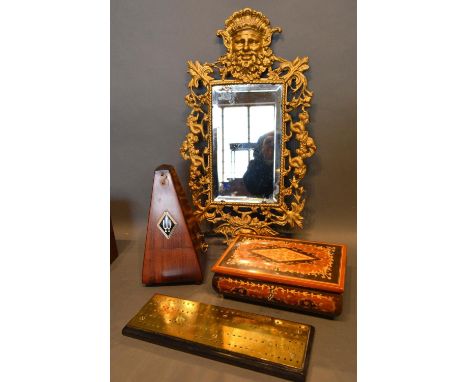 A Brass Wall Mirror Of Pierced Outline And With Mask Head Cresting, 48cm by 23cm, together with a mahogany case metronome, an