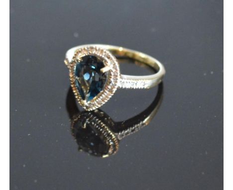 A Yellow Gold Blue Topaz And Diamond Ring set with a teardrop blue topaz surrounded by diamonds and with diamond shoulders wi