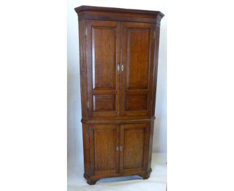 A George III Oak Standing Corner Cabinet, The Moulded Cornice above two panelled doors and two further doors, raised upon oge