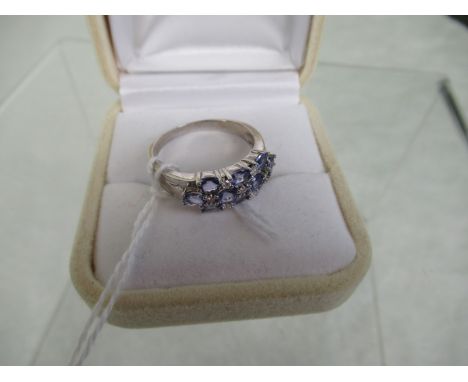 A tanzanite and diamond half-hoop three tier chequer board ring, set with claw mounted oval cut tanzanite and brilliant cut d