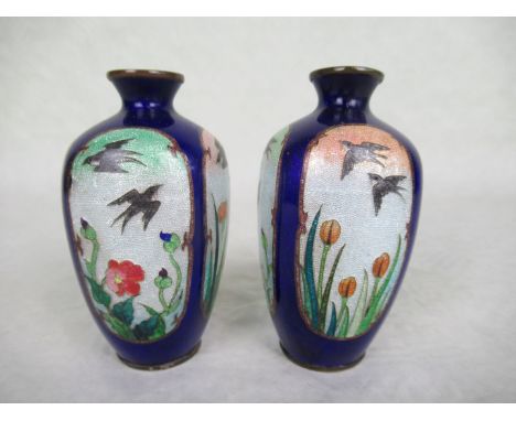 A pair of brass and enamel Japanese vases, circa 1900, depicting birds and flowers within four reserves, cobalt blue finish, 