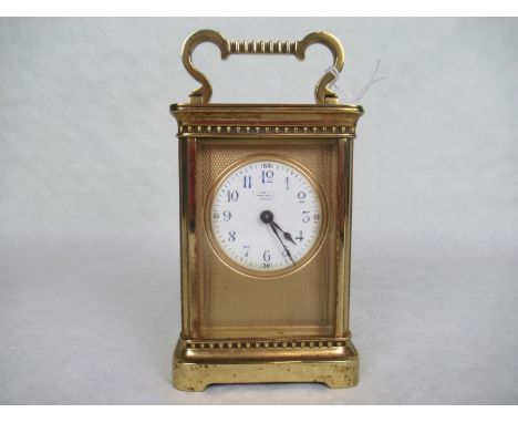 An early 20th century French gilt brass carriage clock, the circular enamel dial bearing Arabic numerals, within an engine tu
