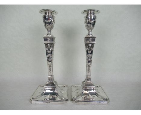 A pair of late Victorian candlesticks, each having relief decoration in the neo-classical form, Sheffield hallmarks 1895 & 18