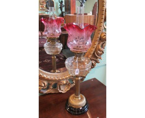 A Victorian oil lamp, having acid etched cranberry glass shade, over clear glass reservoir on brass corinthian-style column, 