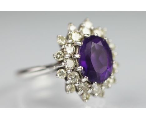 An amethyst and diamond cluster ring, the central oval amethyst within a two row diamond set surround all set in white gold t