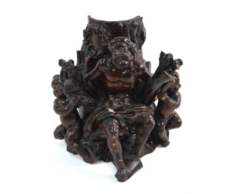 An early 19th century Black Forest (probably) carved wood and brown gesso group of a seated old man flanked by putti, half-pi