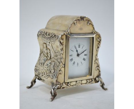 An Edwardian silver boudoir clock embossed with Watteausque picknickers, on scroll feet, William Comyns & Sons, London 1901, 