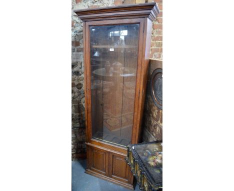 A late 19th / 20th century two part oak gun cabinet in the manner of Army & Navy, the single glazed pane door fitted for five