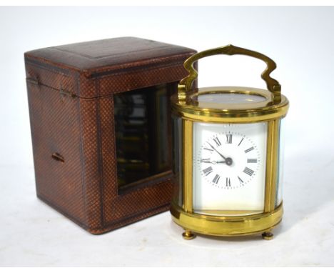 A French oval brass carriage clock with enamel dial, 11 cm high in leather travelling case