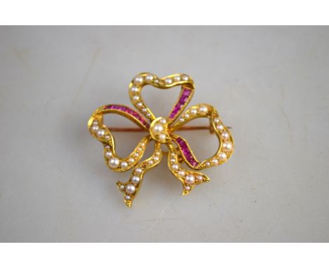 A yellow gold open bow style brooch set with baguette rubies and half pearls stamped 15ct   Condition Report  One half pearl 