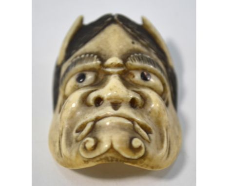 A stained ivory or stag antler netsuke carved as a Hannya mask from the Noh Theatre, the nostrils presumably intended for use