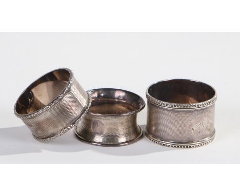Three various silver serviette rings, various dates and makers, each with engine turned decoration, 2.43oz (3)