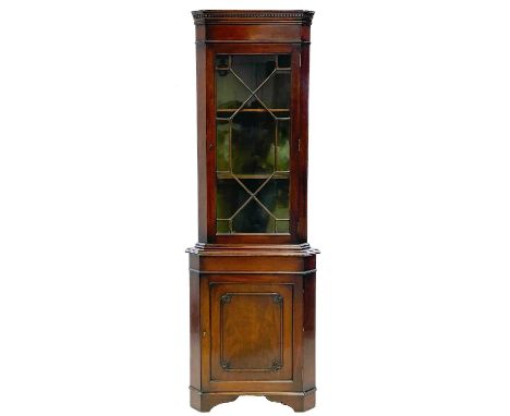 A mahogany standing corner cupboard. 19th century, with a glazed upper part above a panel door with leaf carved quarters to t