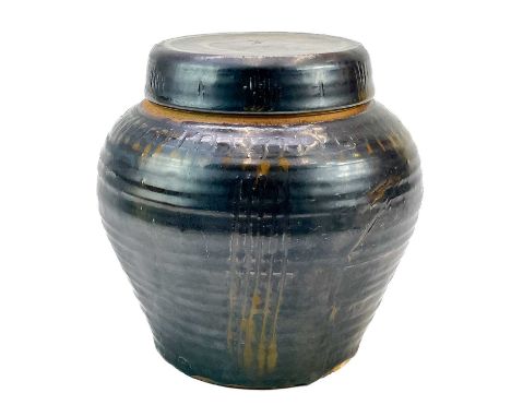 A studio pottery jar with a screw lid.  Height 19cm, with 'M' potters mark, possibly Michael Cardew.No condition issues.