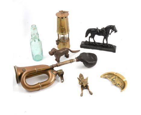 A box of objects, including bottles, miners lamp, dog nut cracker, fox door knocker, etc.