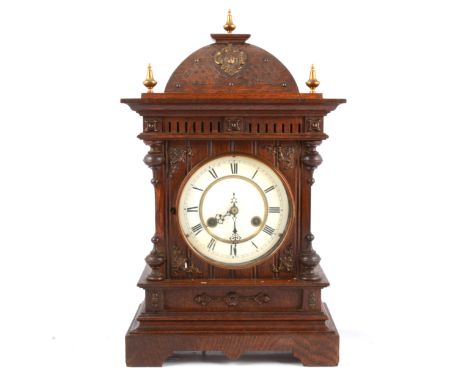 German oak mantel clock, carved oak case with brass finials, white enamel dial, Junghans movement striking on a gong, height 