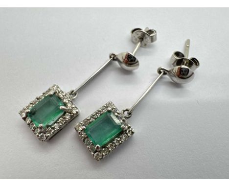 A Pair of Emerald and Diamond Drop Earrings, each emerald cut stone four claw set within diamond halo surround, suspended on 