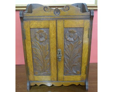 An Arts and Crafts oak smokers cabinet, containing pipe and tobacco pot