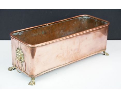 Copper planter with rolled rim, brass drop ring lion mask handles and raised on brass lion paw feet, 42cm long 