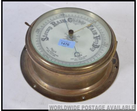 An early 20th century large brass ships bulkhead barometer with detailed white glass dial behind bevelled glass doorf