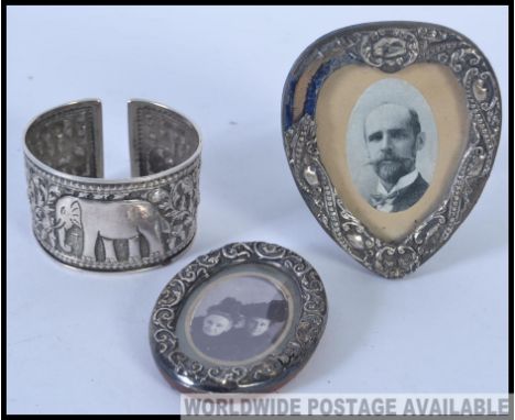 Two silver hallmarked silver easel picture frames, the first being circular and the other being shaped like a heart along wit