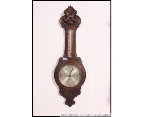 An earrly 20th century aneroid banjo barometer, set in a carved oak surround being marked Selfridge London