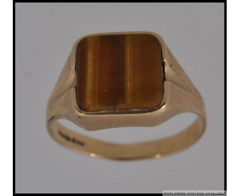 A 9ct gold gentlemans signet ring with inset tigers eye agate stone mount. Hallmarked with makers initials SJ. Total weight 3