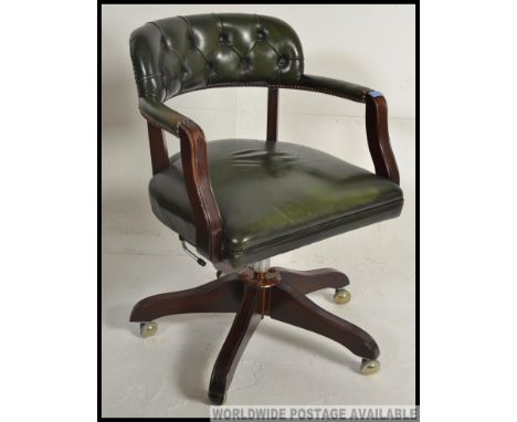 A  20th century antique style green leather and mahogany office swivel chair. Raised on quadruped base with button backed gre
