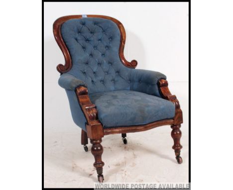 A Victorian mahogany spoon back armchair of large form with blue button backed upholstery to the show wood frame raised on tu