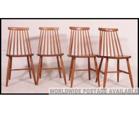 A set of 4 1970's Ercol style stick back beech wood dining chairs. Turned legs united by stretchers with panel seats