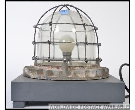 A vintage industrial bulkhead light, converted into a table lamp. Wire cover, with shaped glass on a squared base.