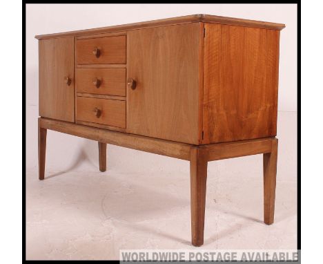 An original Gordon Russell walnut sideboard / dresser. Raised on squared legs with a chest to centre flanked by end cupboards