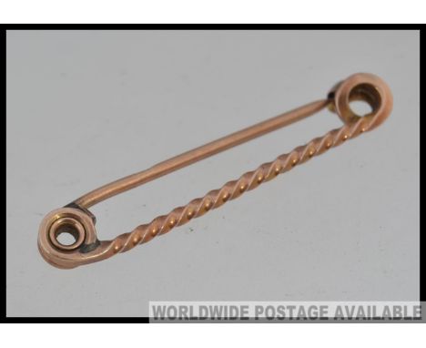 A 9ct gold bar brooch with twisted bar and curled finials with finial clasp. Marked 9ct.  Weight 3.1g. Measures 4cms.