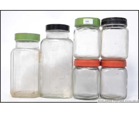 A collection of vintage  / retro glass storage jars with different colour screw twist lids