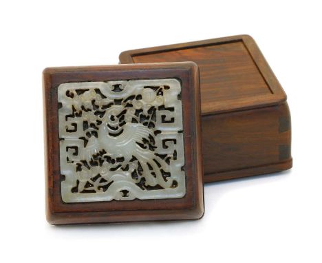 A Chinese jade plaque, carved with a phoenix within a key fret border, 6cm long, inserted on the cover of a wood box, 7.6 wid