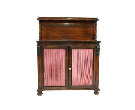 A Victorian rosewood chiffonier, with a raised back shelf on two columns, over a pair of pleated fabric doors, between carved