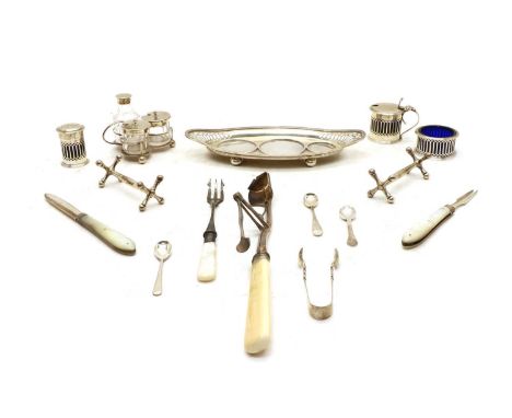 An Edwardian silver cruet on stand, the mustard, salt and pepper having pierced bodies with blue glass liners on a navette fo