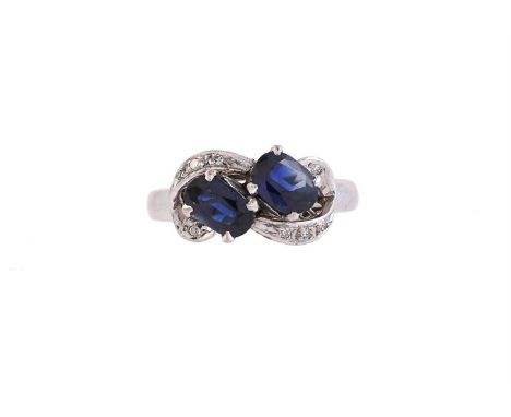 
	
		A TWO STONE SAPPHIRE RING
		The oval cut sapphires within scrolled borders, set with eight cut diamonds, to a scrolled g