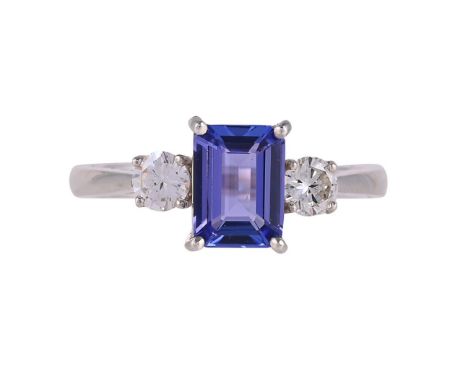 
	
		A THREE STONE TANZANITE AND DIAMOND RING 
		The step cut tanzanite with canted corners, in a four claw setting, between 