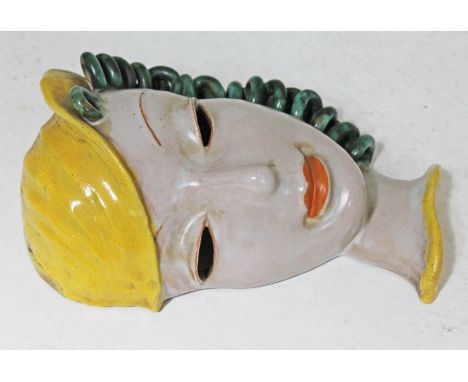 A Goldscheider Art Deco pottery mask formed as a female head with green curls and wearing a yellow hat model no 6428, factory