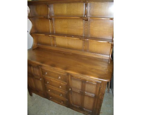 Ercol medium colour elm dresser with two tier raised back above four central drawers flanked by two panelled cupboard doors (