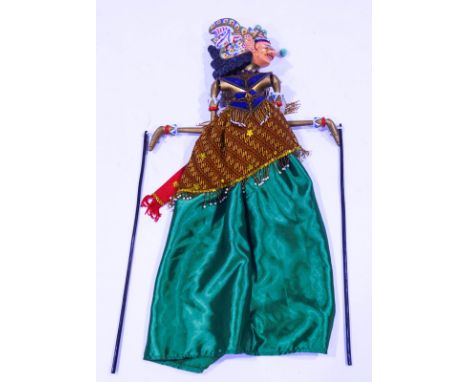 A 20th century Indonesian wooden puppet, with carved and decoratively painted head, beaded and sequinned clothing, 76cm high