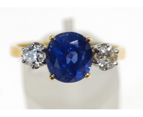 A modern 18ct gold, sapphire and diamond three stone ring, centred with an oval native-cut sapphire approximately 3.20cts, be