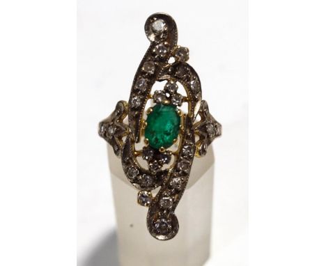 A diamond and emerald ring, unmarked, the central oval cut emerald to a single cut set scrolling head running the length of t