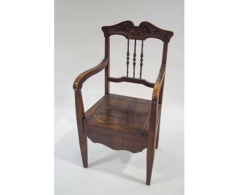 An Edwardian beech commode armchair with carved cresting rail and turned spindles
