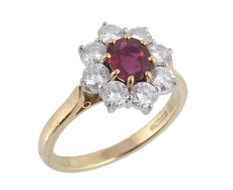  An 18 carat gold ruby and diamond ring by Garrard & Co., the central oval shaped ruby claw set within a surround of brillian