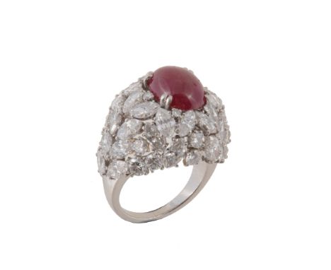 A French ruby and diamond cluster ring, the central oval cabochon ruby claw set within a surround of brilliant cut and marqu